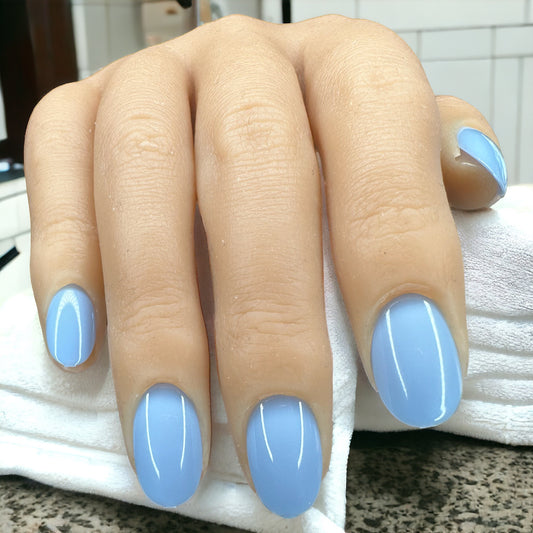 fingers laying on a white towel, wearing short round sky blue press-on nails