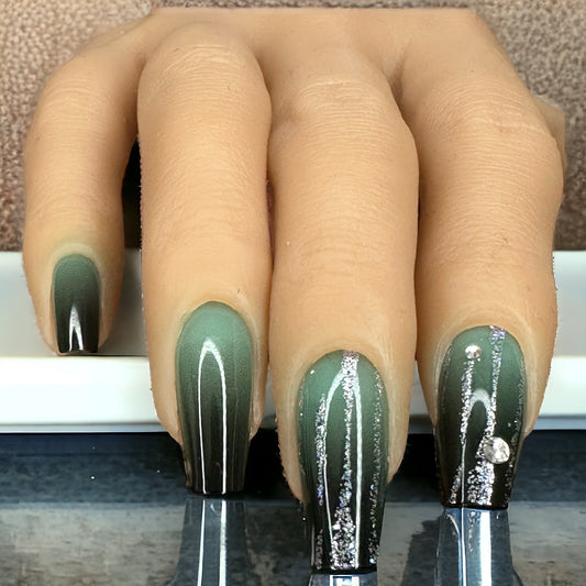 Hand adorned with long coffin-shaped press-on nails in green Ombre color with rhinestones