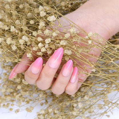 Hand featuring pink ombre almond-shaped press-on nails against white flowered background