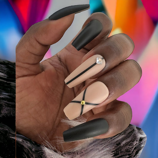 Hand with long coffin-shaped black and beige press-on nails with rhinestones against a colorful background