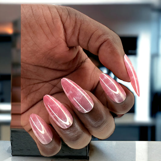 Hand with pink marble almond-shaped press-on nails against a white background