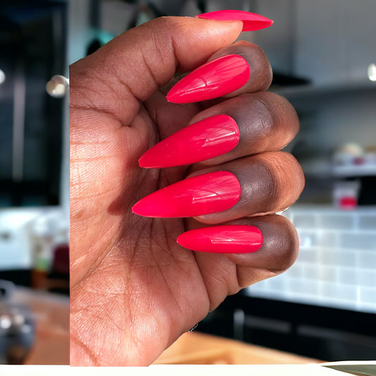 Hand showing fingers in Tart red long stiletto press-on nails on a neutral background