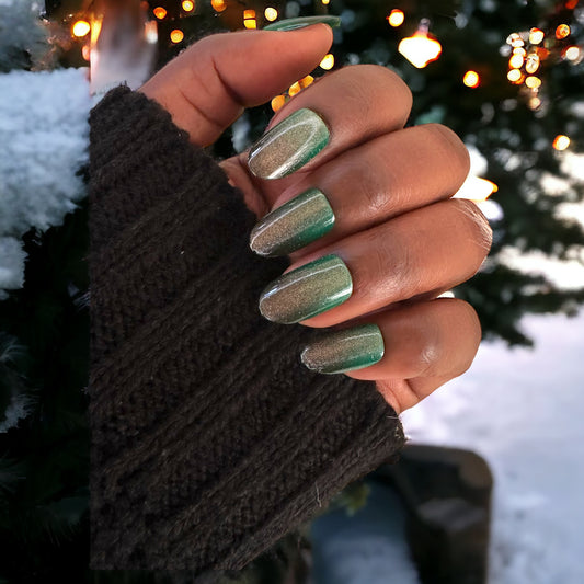 Fingers with short round press-on nails in green cat eye color, set against a background of twinkling tree lights