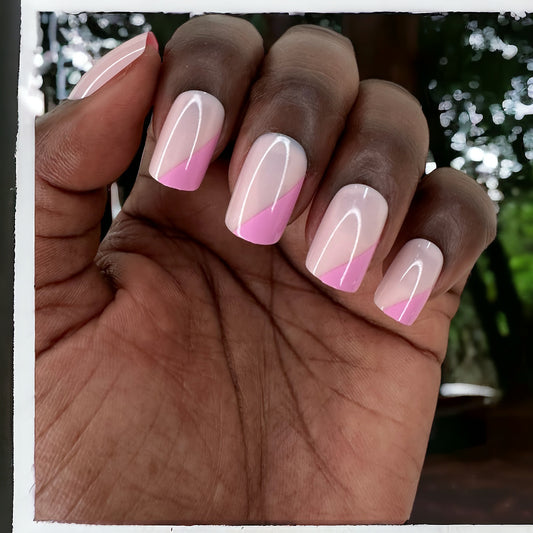 Fingers adorned with short square pink monochrome press-on nails against a backdrop of trees