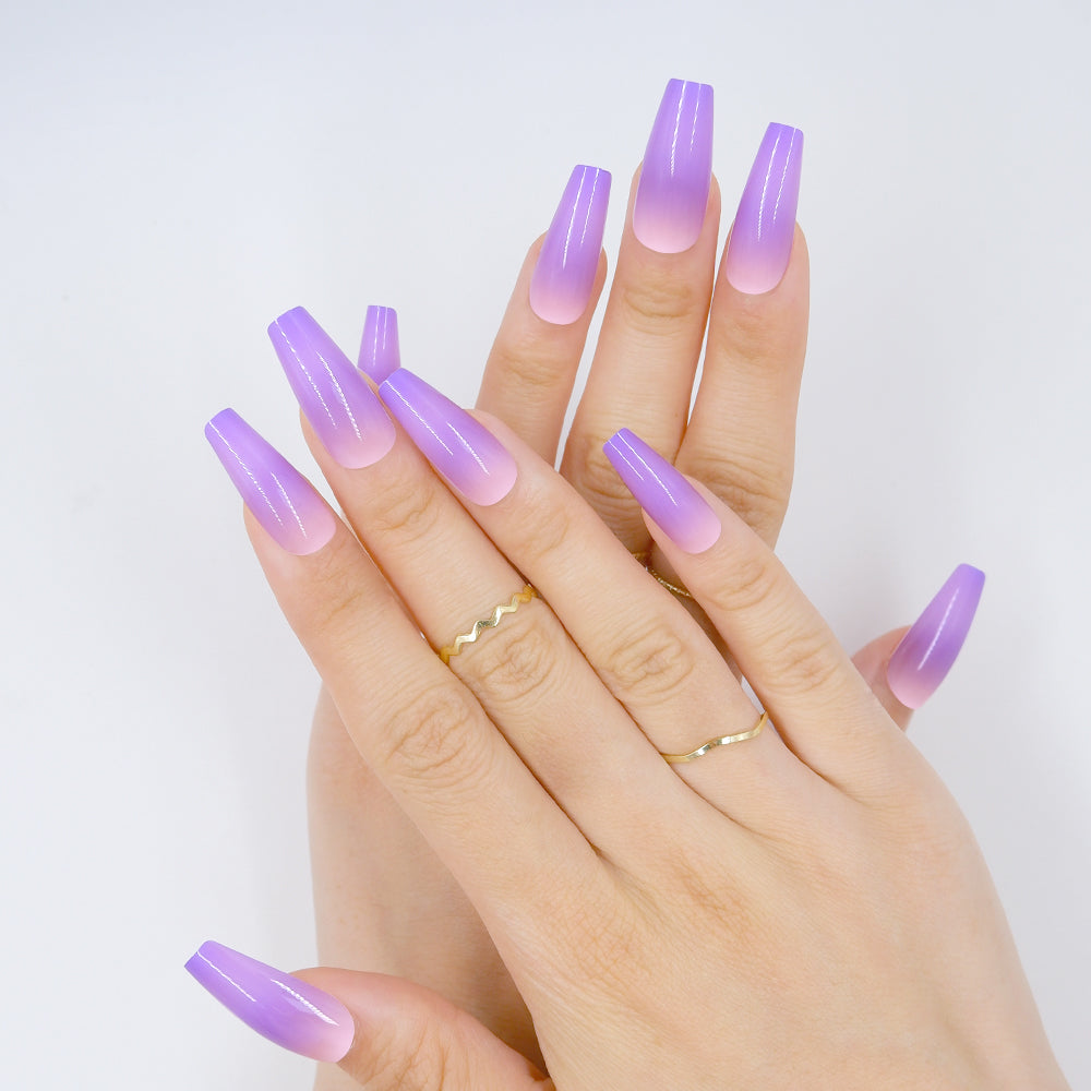 Hand with long coffin-shaped press-on nails in violet color against a white background