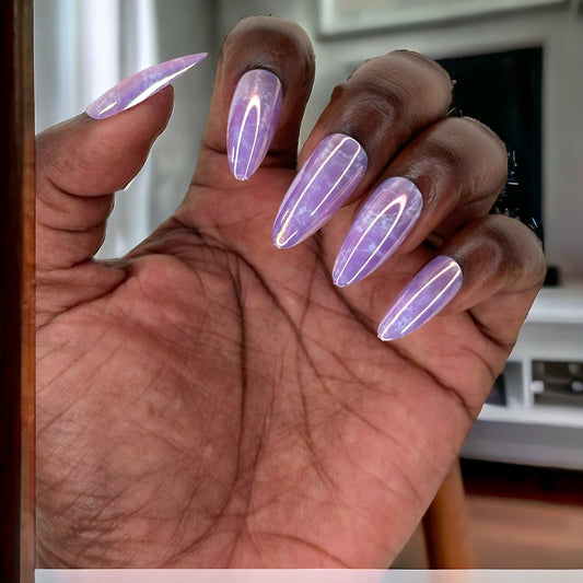 A hand displaying almond-shaped press-on nails with a violet marble pattern, set against a neutral background