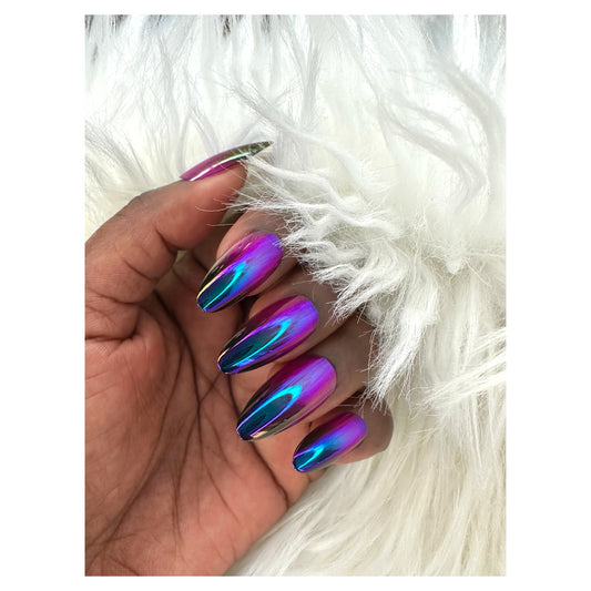 A hand with almond-shaped press-on nails featuring a purple chrome ombre design, resting on a soft, fluffy white fabric